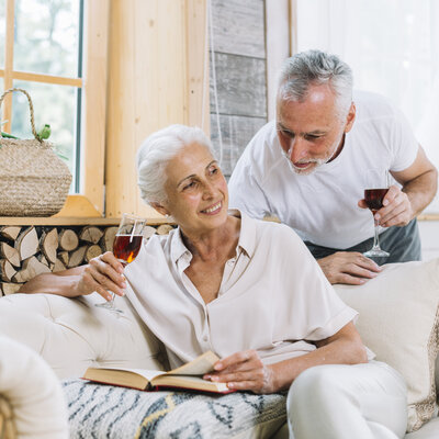 7.senior-man-looking-her-wife-sitting-sofa-with-book.jpg